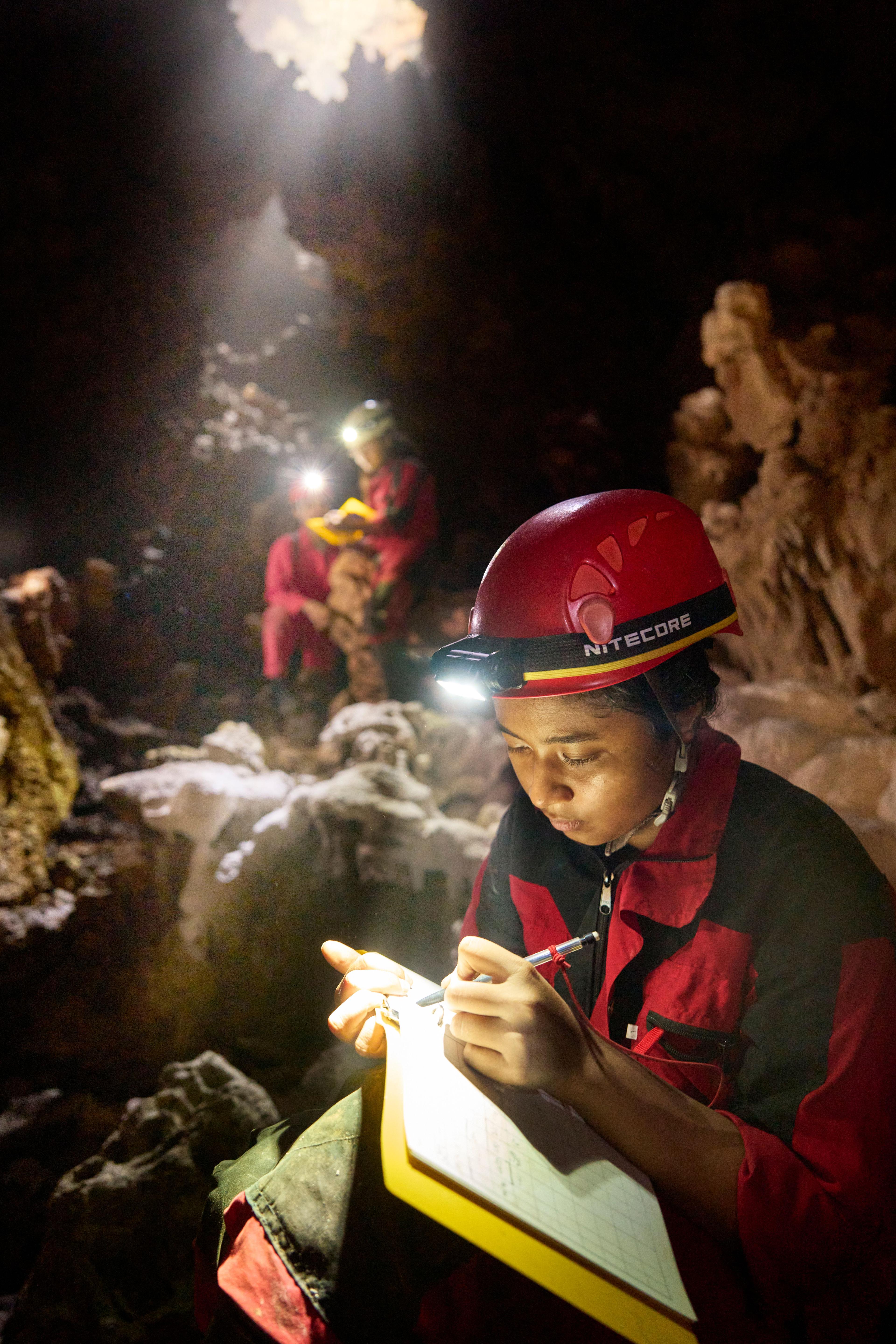 Woman in a cave taking notes