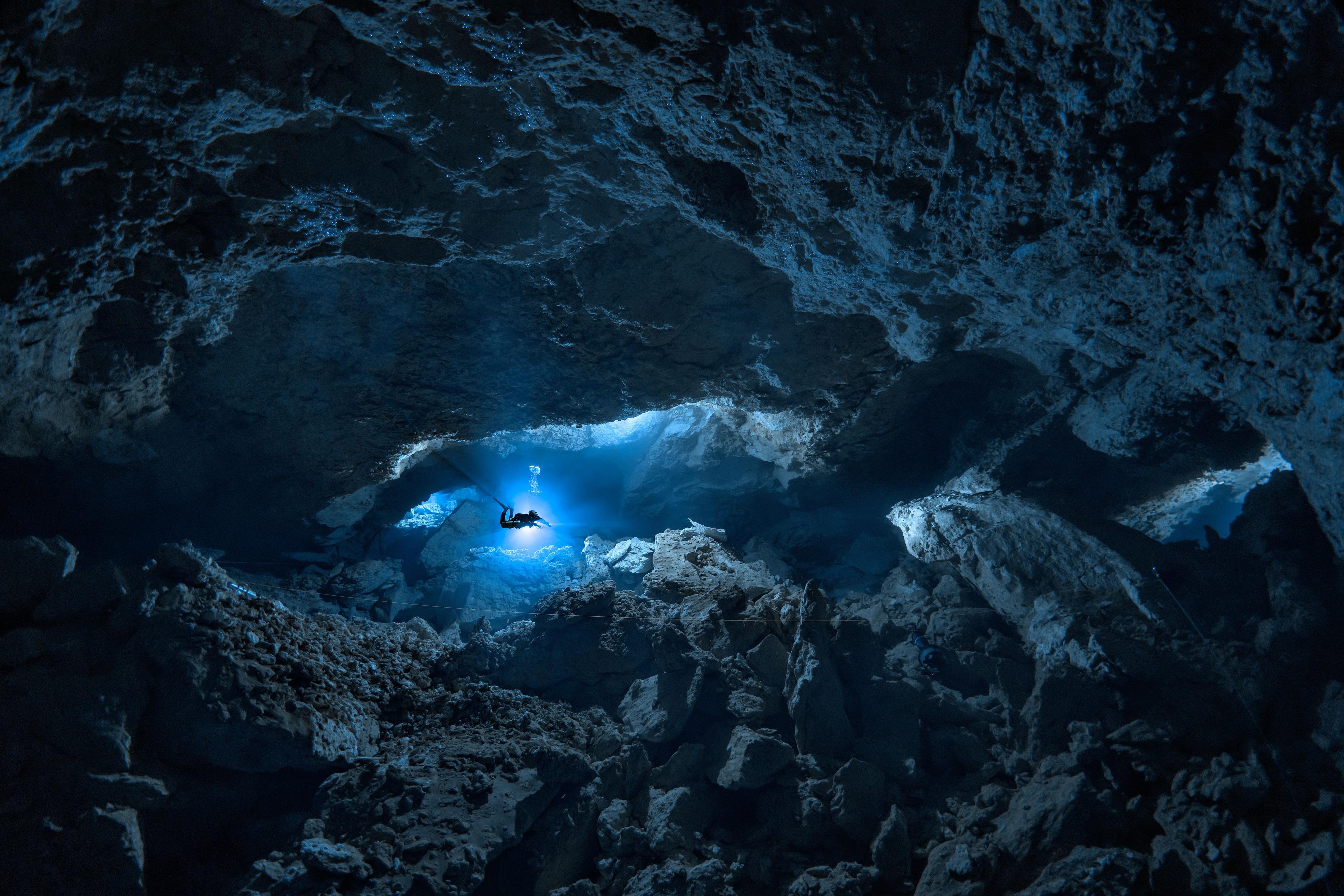 Diver at a distance in a huge underwater cave - Image by Alex Dawson