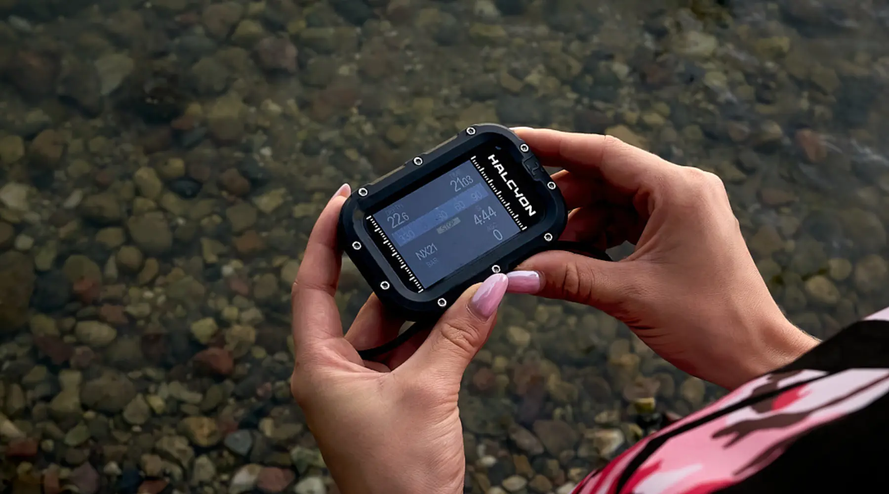Woman holding Symbios computer in her hand next to a lake